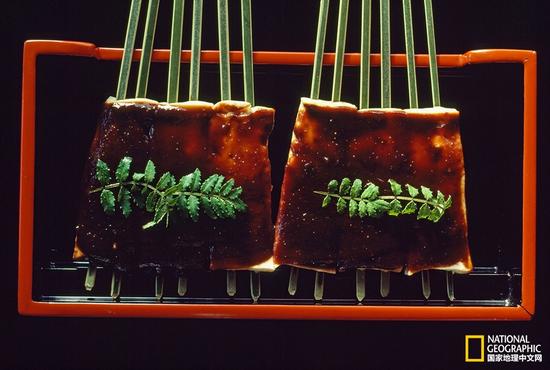 装饰着小菜叶的田乐，这是将豆腐用钎子串起来后抹上味噌再烧烤的一种菜。