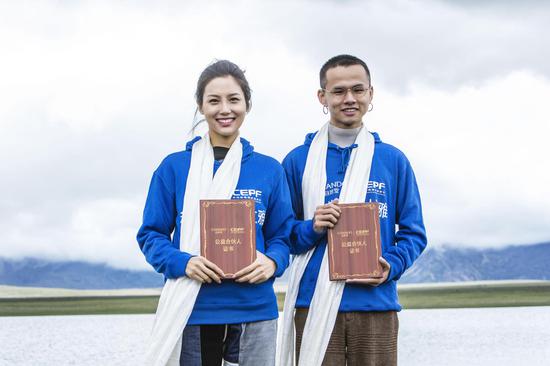 知名艺人艾克里里（右）、模特演员张昊玥（左）在日喀则自然堂草场被授予“自然堂喜马拉雅公益合伙人”证书