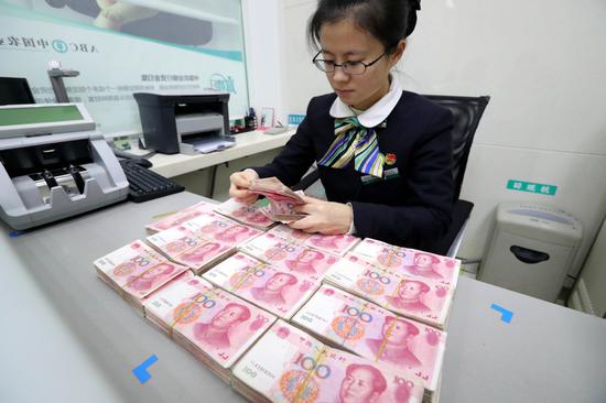 A clerk counts cash at a bank in Huaibei， Anhui province． [Photo provided to China Daily]