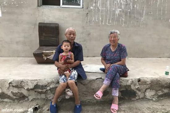 辽宁朝阳市山咀村，下午五点半，两位老人怀抱孙女在此闲坐。少子老龄化正威胁着辽宁城乡的正常运转。（南方周末记者 杜茂林/图）