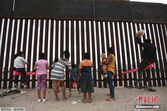 资料图:美国加州两位教授利用美墨边境高墙的空隙,设置了横跨两国的跷跷板,跷跷板一边在美国,一边则在墨西哥,让美墨两边的大人小孩隔着高墙仍能一同玩耍。