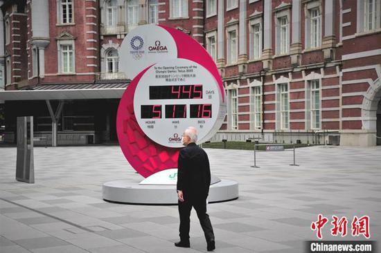 当地时间5月4日，行人走过日本东京车站附近的奥运倒计时电子屏。当天，日本首相安倍晋三在新冠病毒感染症对策总部会议上宣布，以全国为对象的“紧急事态宣言”期限延长至5月31日。 中新社记者 吕少威 摄