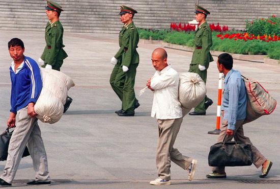 (上世纪八九十年代,扛着大包小包进城务工的农民。图/法新)