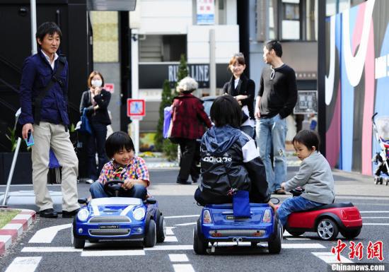 资料图：几名日本儿童在家人的陪伴下乘坐玩具电动车。中新社发 侯宇 摄