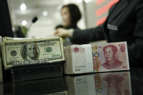 　2010年4月13日，安徽省淮北市，某银行工作人员正在清点美元、人民币。 视觉中国 资料图