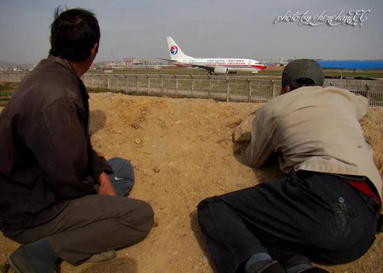 照片为昆明机场外农民工看飞机起降