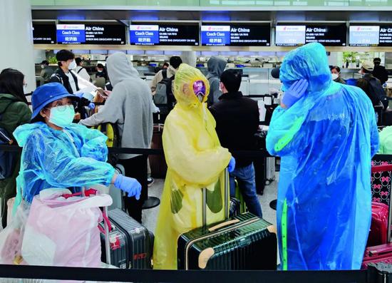 3月26日，美国旧金山国际机场，前往中国的乘客采取严密防护措施，排队办理登机手续。摄影/本刊记者 刘关关 