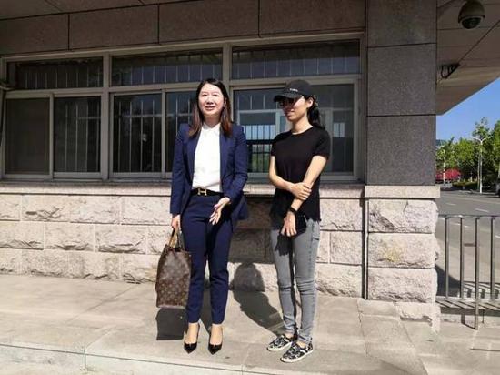 应莹(戴帽者)和代理律师在监狱门口等待开庭。