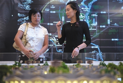 9月15日，售楼小姐郭然（右）向客户介绍楼盘概况。本版摄影/新京报记者 吴江