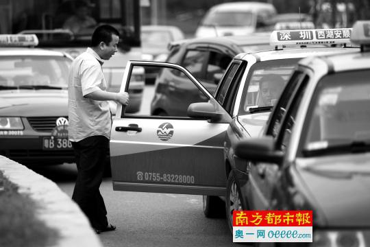     深圳街头，一位红的司机正在招揽搭乘绿的换乘的客人。未来这两种出租车的价格将统一。南都记者赵炎雄 资料图片