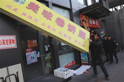 昨日下午，丰台区食药监局执法人员对涉嫌违法经营的店铺招牌进行拆除。新京报记者 吴江摄