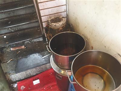 “有饭炸鸡”店铺旁狭窄过道内,潲水桶、盛着油渣的圆桶、面粉等堆在一起,地上散落着烟头、卫生纸、砖块。新京报记者 张越摄