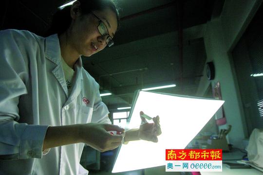     往复式摩擦测试后，试验员在展示手机膜。