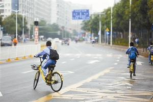 小学生在机动车道路上骑共享单车。