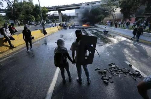 2017年4月24日，在委内瑞拉加拉加斯，一对夫妇在反政府示威者设置的路障旁。抗议者封锁了首都的主干道，以表达对马杜罗总统统治的厌恶。