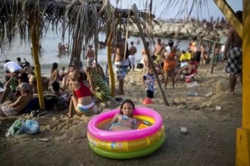 2014年3月3日，一名女孩在委内瑞拉La Guaira一个充气游泳池里玩水。尽管全国范围的反对派抗议持续了两周，一些委内瑞拉人仍不忘过狂欢节。
