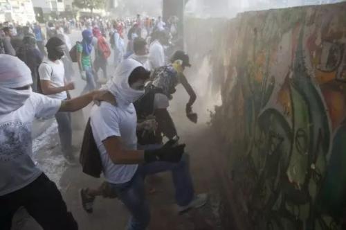 2014年3月4日，查韦斯去世一周年之际，委内瑞拉首都加拉加斯的反政府抗议，人们摧毁一堵墙，以便向警方投掷更多的石块。