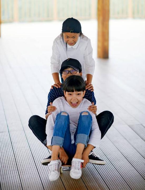 安新县，三个女孩在栈桥玩滑板。摄影/甄宏戈