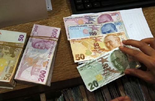8月15日，在土耳其伊斯坦布尔的货币兑换处，一名工作人员展示土耳其里拉纸币。 