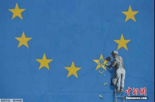 当地时间2017年5月7日,英国多佛,一名街头艺术家班克西创作了一幅画,画面中一名工人正从欧盟12星旗帜上抹掉一颗星,寓意着英国将脱离欧盟。