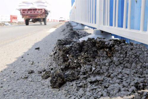 西半幅几十米路面的沥青和石子翘起，有多处裂缝，看上去伤痕累累 图源：河南网