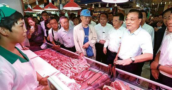 2019年8月20日，国务院总理李克强（右二）在哈尔滨考察期间到菜市场了解猪肉价格变动和销售情况。图/中新社