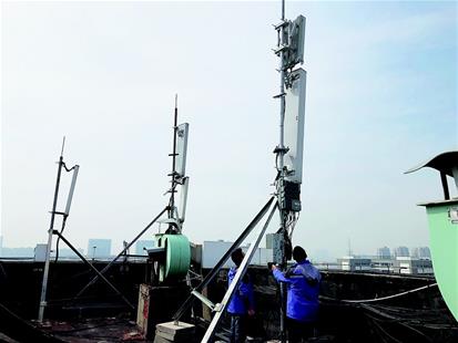 图为：在武汉光谷一学院教学楼顶楼，湖北移动公司的一座基站集成了2G、4G和5G设备。基站天线（右一）最顶层是4G天线，中间层是2G天线，最下层是5G天线。 （记者 刘天纵 摄）