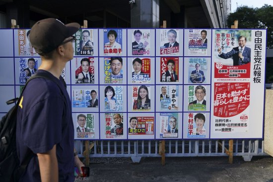 7 月 20 日,东京,一名行人看着自民党候选人与石破茂(右)的海报。