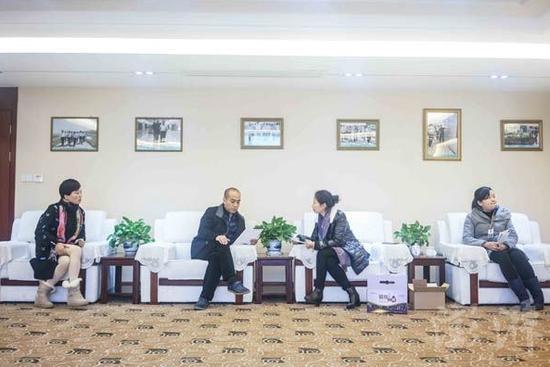 叶照辉在会议室和客户谈业务,墙上挂着各级政府领导来到公司考察的照片。