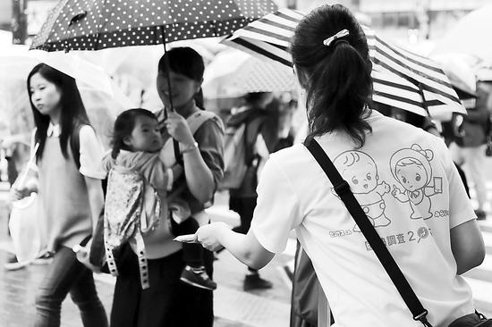 2015年9月10日,日本启动全国人口普查。图为东京街头,一女子向路人发放资料。(图片来源:环球时报)