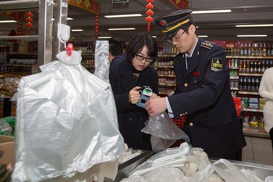 3月17日，上海株洲路联华超市，质监执法人员用测厚仪对“三无”塑料袋进行测量。 澎湃新闻记者 朱伟辉 图