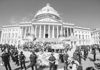4月18日，上千名民众在华盛顿国会山举行抗议示威，要求国会采取行动结束政治腐败并确保选举自由公正。图为警察将示威者驱赶至外围，自愿被逮捕的示威者可留在圈内。据抗议示威组织者称，当日有数百名抗议者被警方逮捕。

　　新华社发
