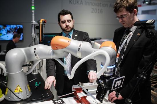 2016年4月27日，在德国汉诺威工业博览会上，工作人员在德国库卡机器人公司展区展示机器人手臂。新华社发