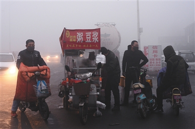 2016年12月22日早7时许，河北钢铁集团邯钢公司门口。工人在雾霾中戴着口罩买早餐。