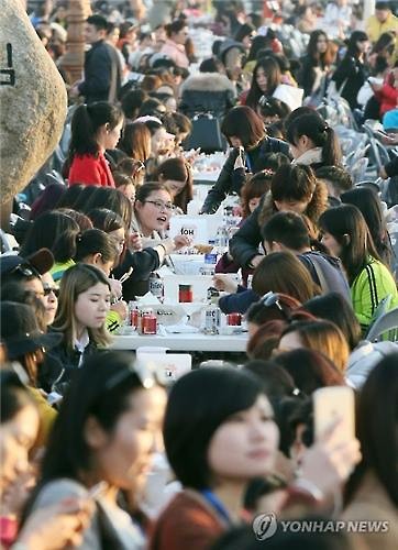 资料图片：2016年3月28日下午，在仁川市月尾岛文化街，几千名傲澜员工一起吃炸鸡喝啤酒。（韩联社）