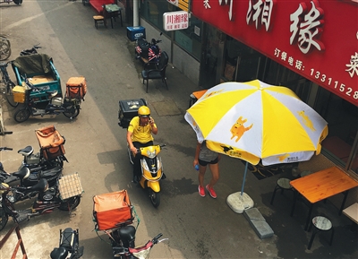 2016年8月5日，五道口购物广场，一名美团外卖的送餐员正经过一家餐馆门口。新京报记者 尹亚飞 摄