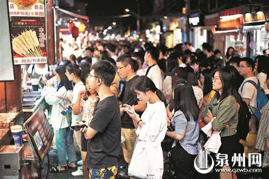 昨日晚上,西街一些小吃店前,游客排长队等待购买。(陈晓东 摄)