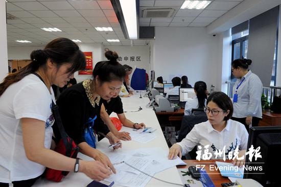 市医保中心内,工作人员正在耐心为市民办理业务。