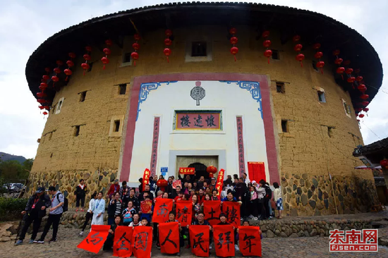 春节前夕,游客在南靖土楼与当地群众一同举起灯笼、春联,向全国人民拜年