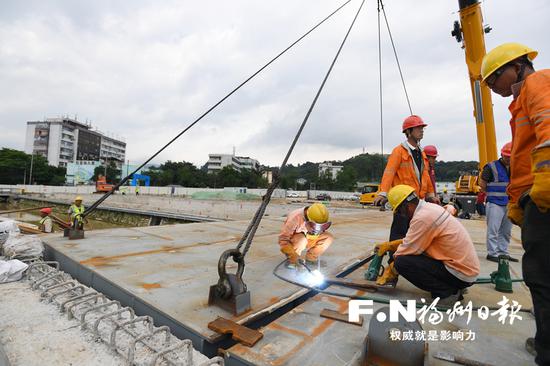 工人在进行站东路延伸段工程钢箱梁吊装焊接。
