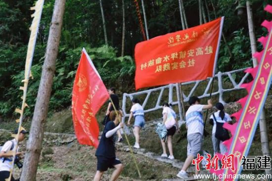 大学生们举着红色筑梦之旅的旗帜，走在先辈们浴血奋战的土地上，攀登着人类不屈不挠的精神高地