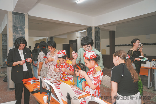 在乌兹别克斯坦，周冬梅教当地小朋友剪纸