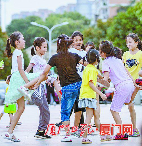 昨日天气依旧闷热,图为傍晚孩子们在一起玩耍。(记者 张奇辉 摄)