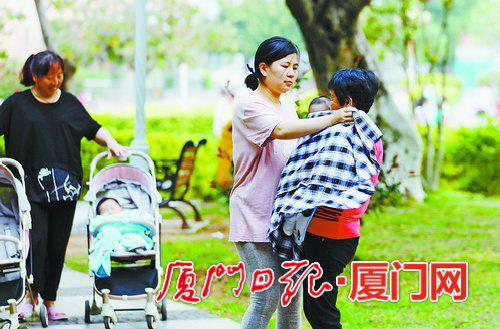 昨日傍晚起风降温,家长为孩子添加衣物。(本报记者 张奇辉 摄)
