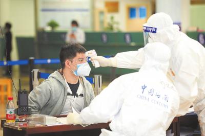 旅客在入境大厅的卫生检疫查验台接受海关关员的医学排查等。