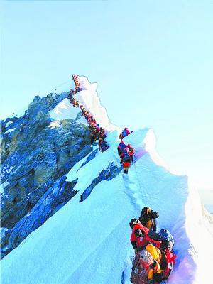 ■图为热传的珠峰拥堵照片,登山者排成的“长龙”蜿蜒在通向顶峰的狭窄山脊上。 资料图
