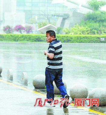昨日,一名没带伞的行人用塑料板遮雨。