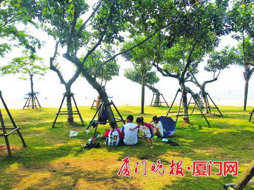 ■草地上,不少人席地而坐。