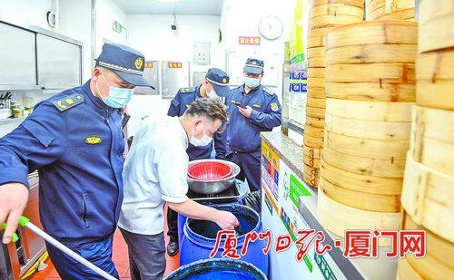 执法人员认真检查餐饮店厨余垃圾的分类投放情况。