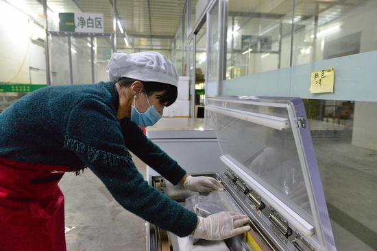 员工操作机器在对黑鸡产品进行真空包装